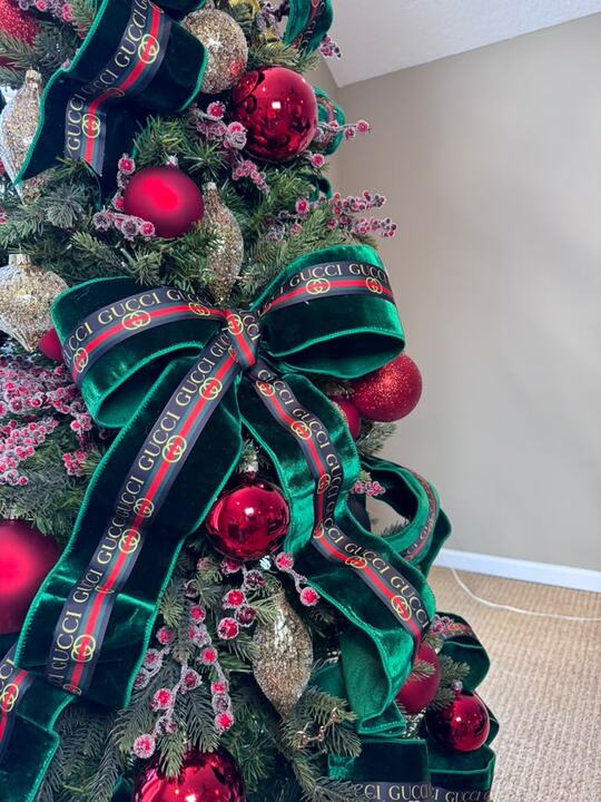 Close-up of an emerald velvet bow with striped couture ribbon and red ornaments