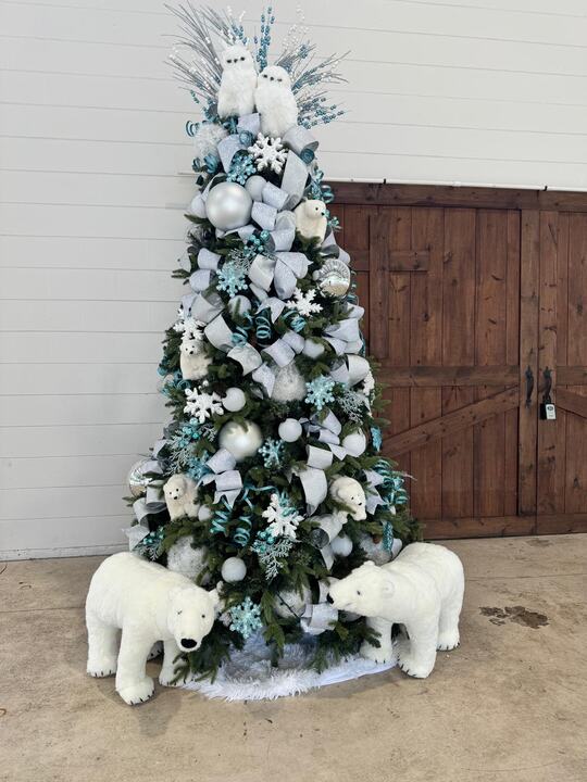 White and silver tree flanked by plush polar bears in front of a barn door